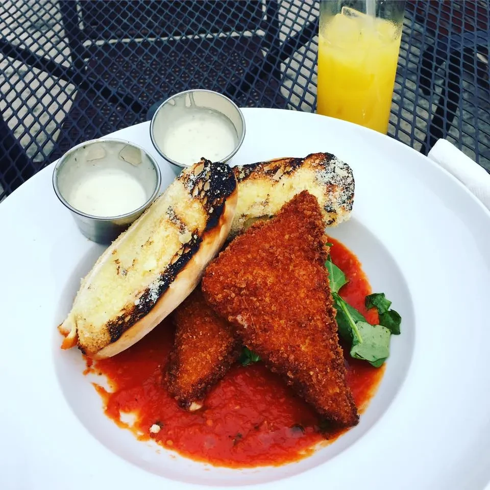 Close-up meal: breaded cutlets, tomato sauce, grilled vegetables, dipping sauce.