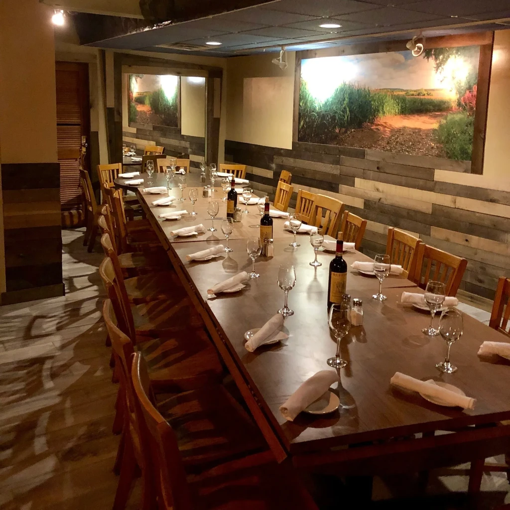 Warm private dining room, long wooden table set with wine glasses.