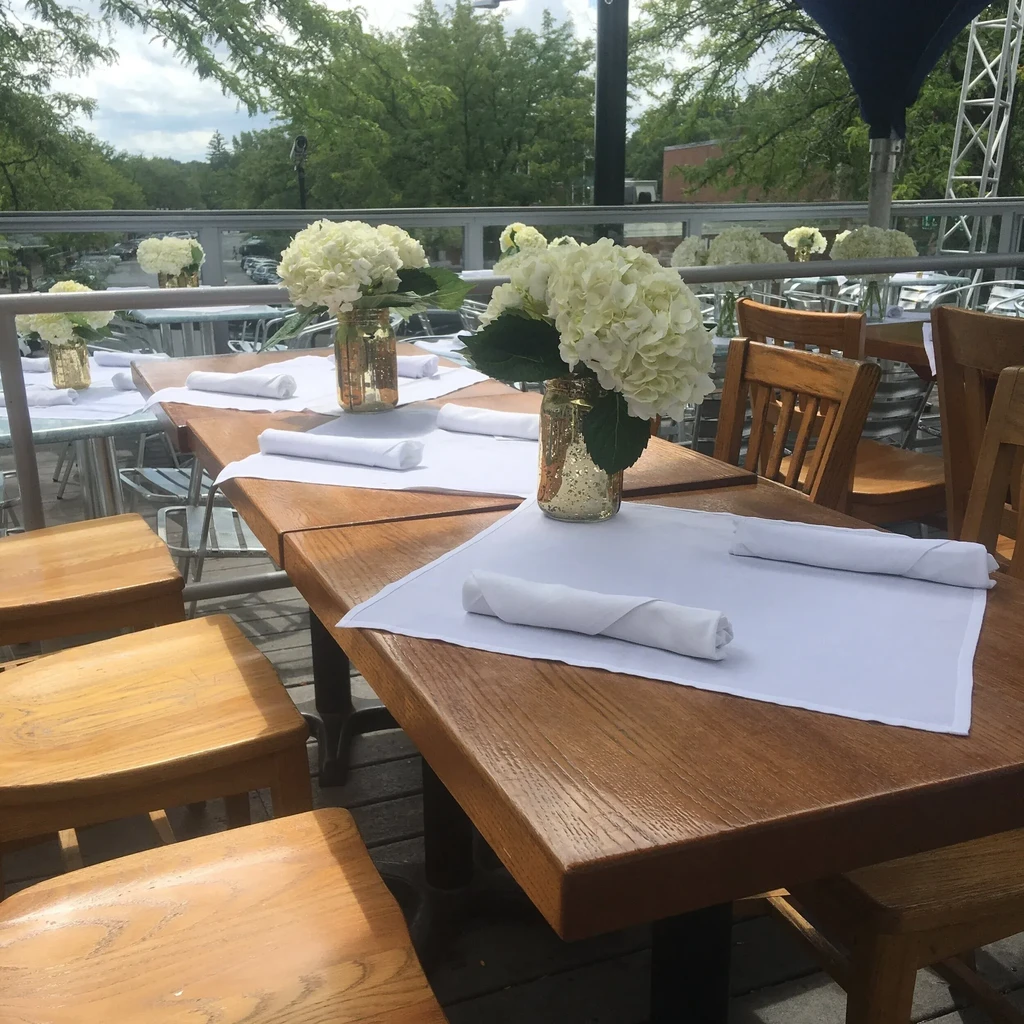 Empty outdoor patio with wooden tables decorated with white hydrangeas.