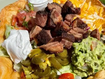 Vibrant taco salad in a crispy tortilla bowl with meat and toppings.
