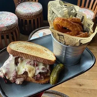 Deli sandwich with melted cheese, dill pickle, and crispy onion rings.