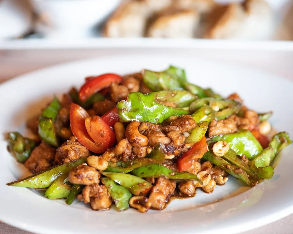 Close-up of stir-fried chicken with vegetables, cashews, and dark sauce.