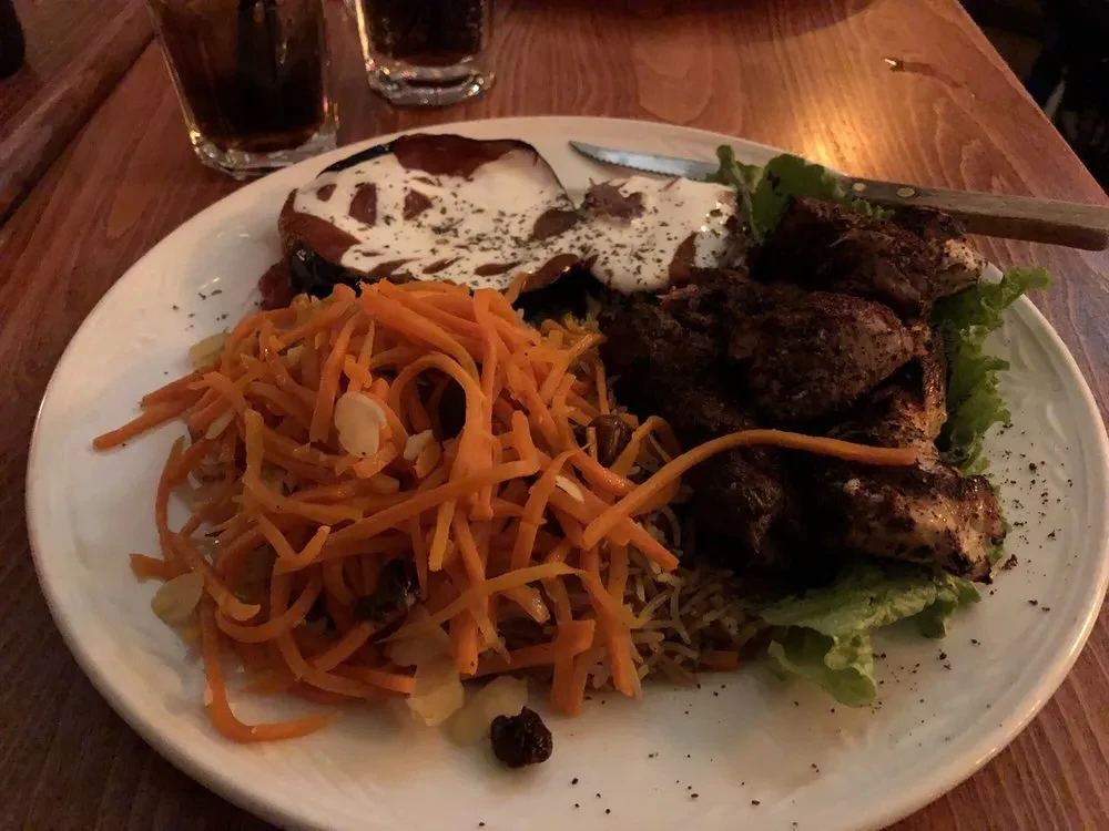 Overhead: Grilled meat, roasted vegetable, and carrot salad on a plate.