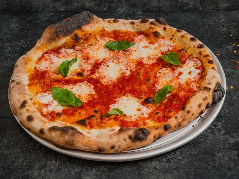 Neapolitan Margherita pizza with charred crust, tomato, mozzarella, and basil.
