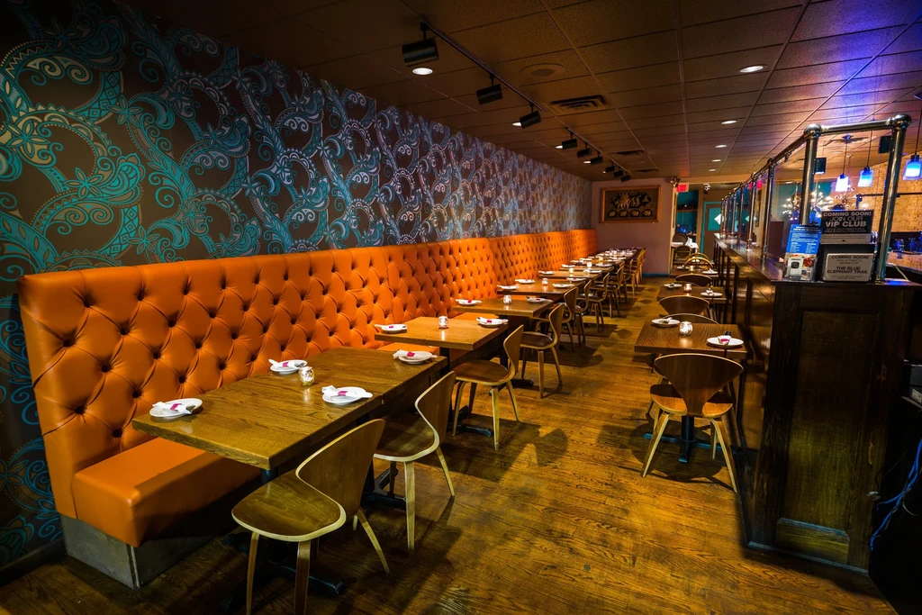 Interior of The Blue Elephant Bar: orange booth, paisley wallpaper, tables.