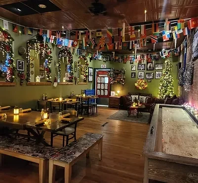 Rustic restaurant interior, Christmas decor, international flags, and shuffleboard.