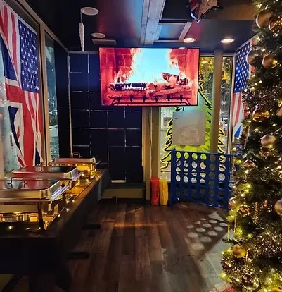 Decorated event room: buffet, US/UK flags, fireplace TV, Christmas tree.