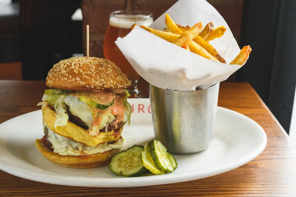 Double-patty burger with cheese, lettuce, pickles, fries, and beer.