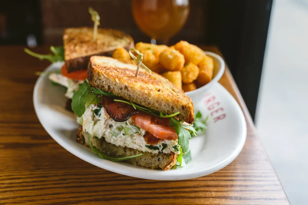Grilled sandwich with chicken/tuna salad, bacon, and tater tots.