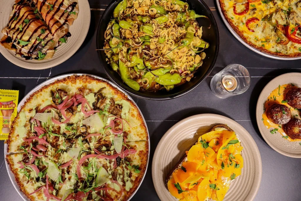 Overhead: Six diverse dishes and a lit candle on a dark table.
