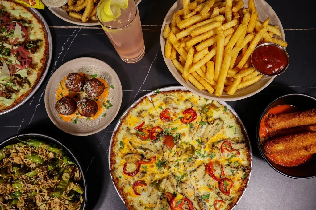 Flat lay view of a dark table laden with diverse food and drinks.