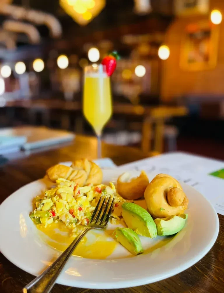 Plate with scrambled eggs, peppers, avocado, and golden-brown bread.