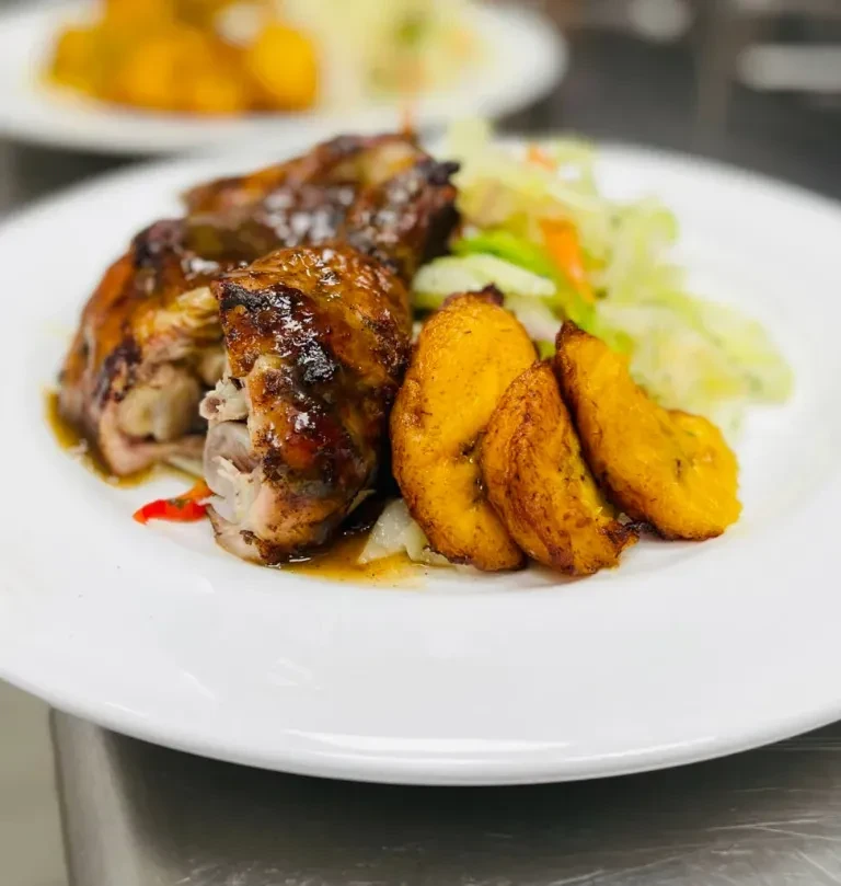 Glazed chicken, fried plantains, and salad served on a white plate.