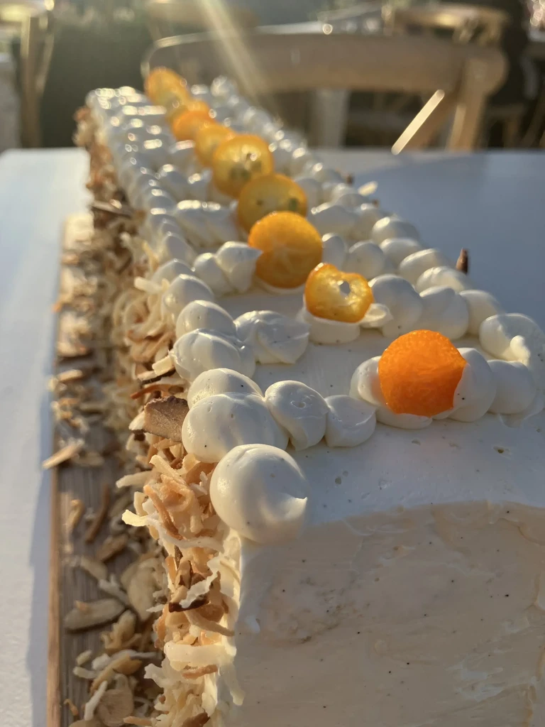 Rectangular dessert with vanilla bean frosting, kumquats, meringue, coconut, almonds.
