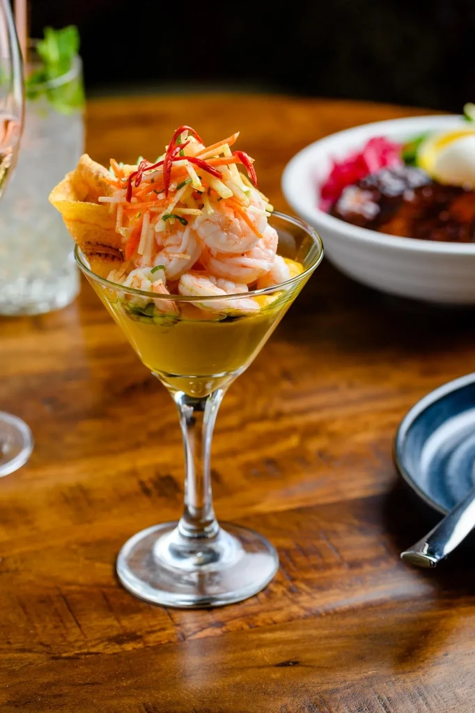 Vibrant shrimp cocktail with vegetables and sauce in a martini glass.