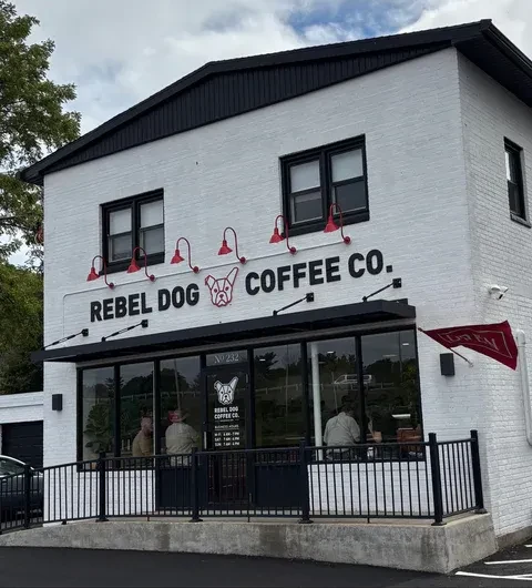 Modern white brick building housing Rebel Dog Coffee Co. with ramp.