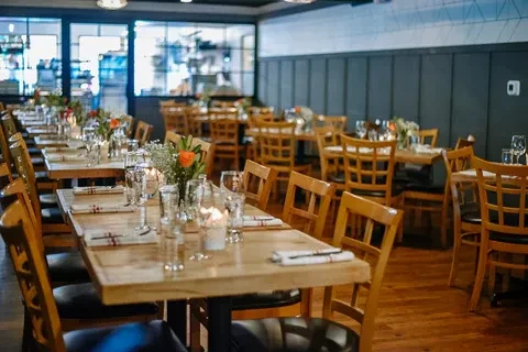 Empty restaurant dining room with set wooden tables and lit candles.