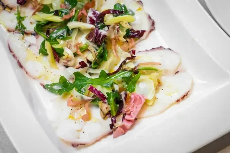 Thinly sliced octopus carpaccio with mixed greens and radicchio salad.