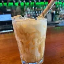 Creamy marbled drink with ice, wafer garnish, on a bar.
