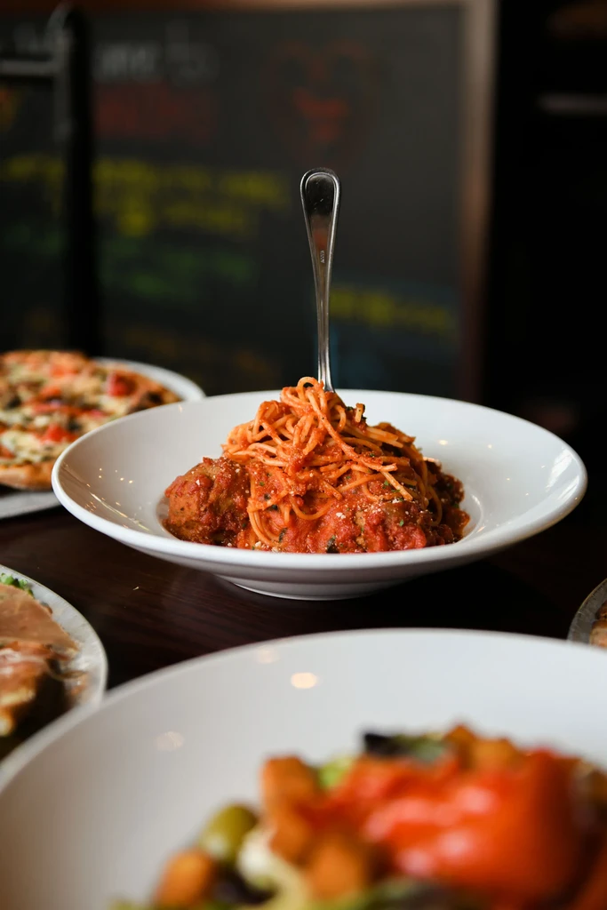Dish of spaghetti and meatballs, fork lifting sauce-coated strands.