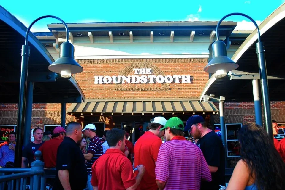 The Houndstooth brick building's patio bustling with a large crowd.