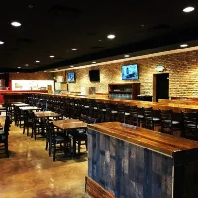 Empty modern rustic bar interior with wooden bar and TVs.