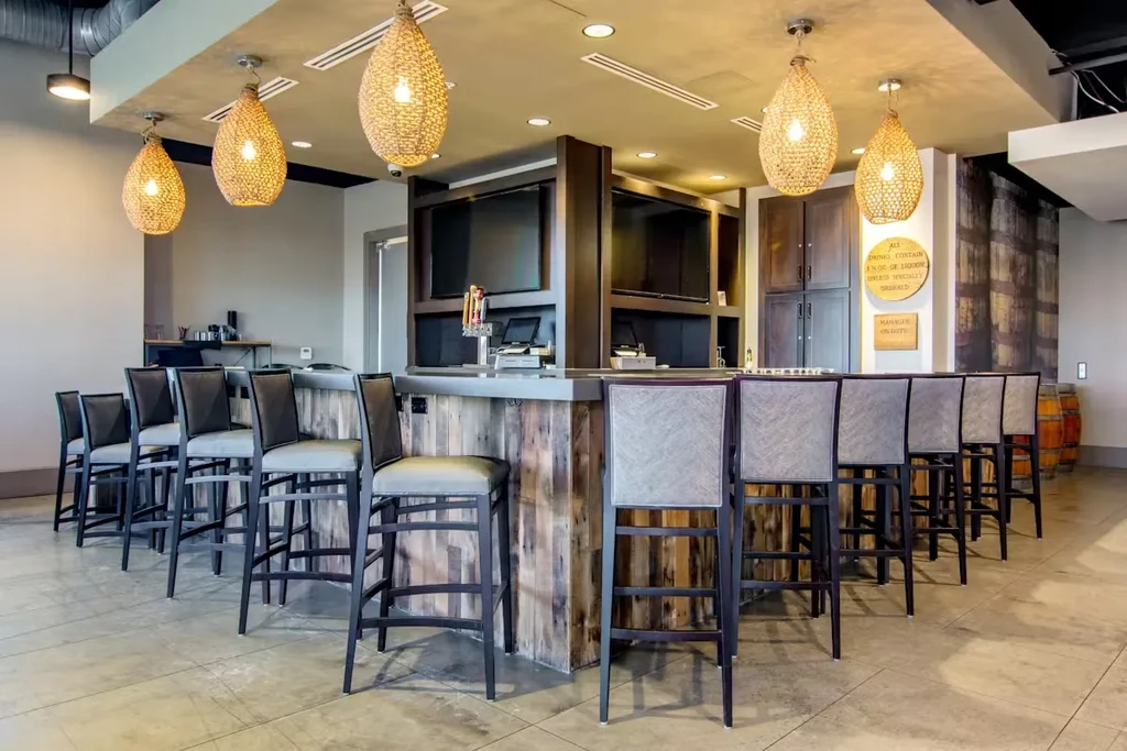 Modern rustic-chic bar with wooden counter, stools, beer taps, and pendant lights.