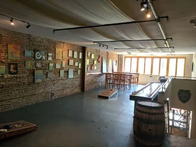 Spacious industrial-chic bar interior with brick wall art and games.