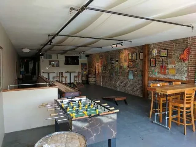 Bright, industrial-chic bar interior with games, high-top tables, and brick.
