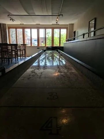 Long shuffleboard table with visible numbers in a bar game room.