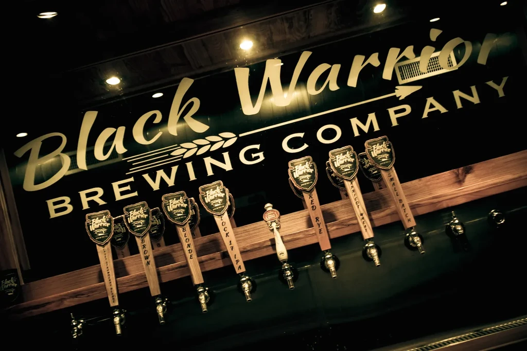 Prominent Black Warrior Brewing Company sign above illuminated beer taps.