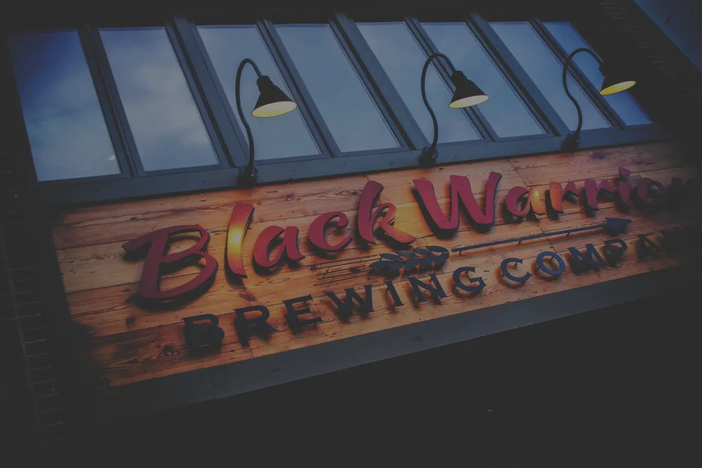 Illuminated wooden sign for Black Warrior Brewing Company with red script.