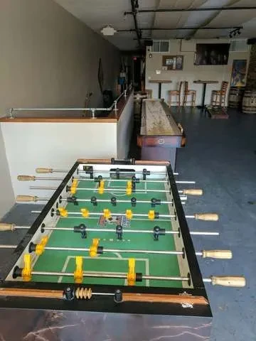 Foosball and shuffleboard tables in a casual game room.