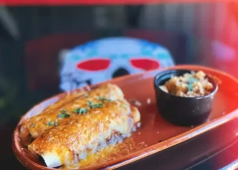 Two baked dishes with melted cheese and herbs, side of rice.