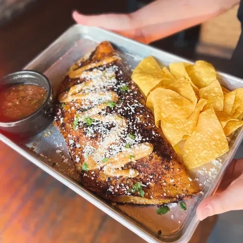 Golden-brown dish with cheese and herbs, served with salsa and chips.