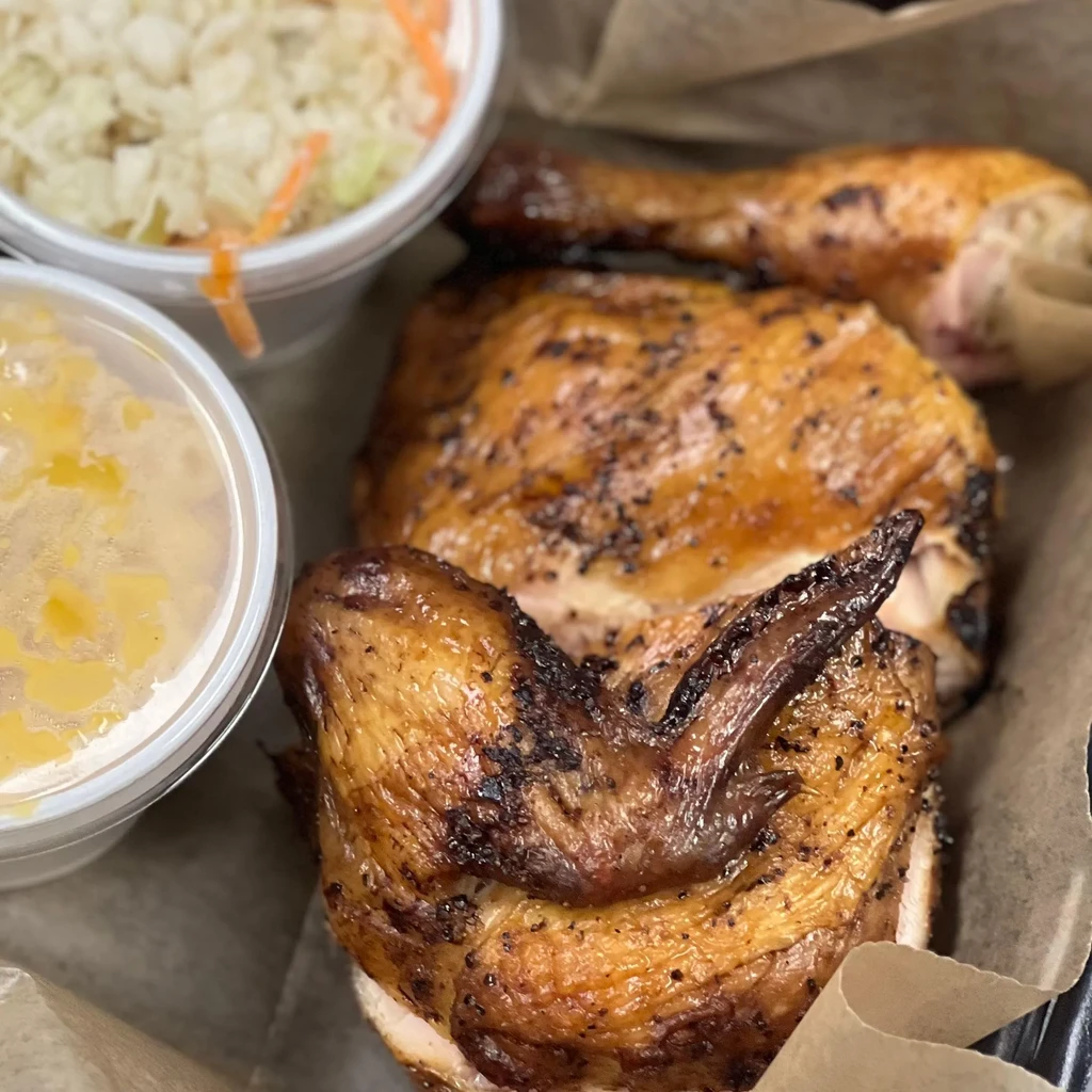 Takeout meal with seasoned roasted chicken, coleslaw, and macaroni and cheese.