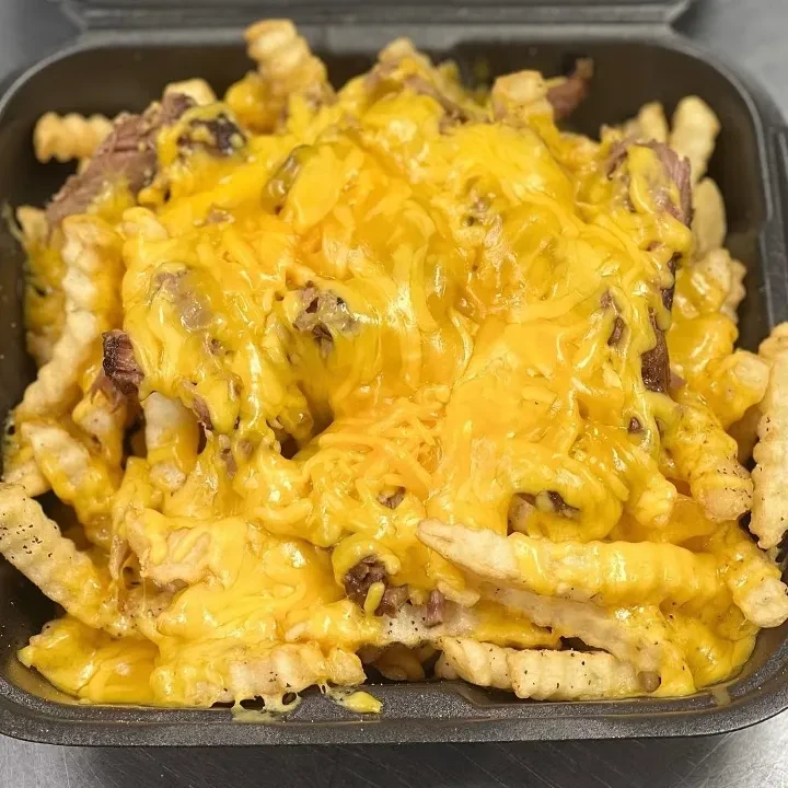 Crinkle-cut fries with melted cheese and shredded beef in takeout container.