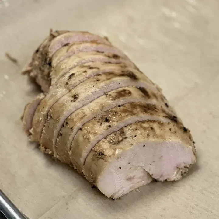 Sliced, seasoned cooked poultry breast on a light surface.