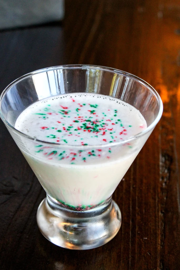 Close-up of creamy drink in martini glass with red-green sprinkles.