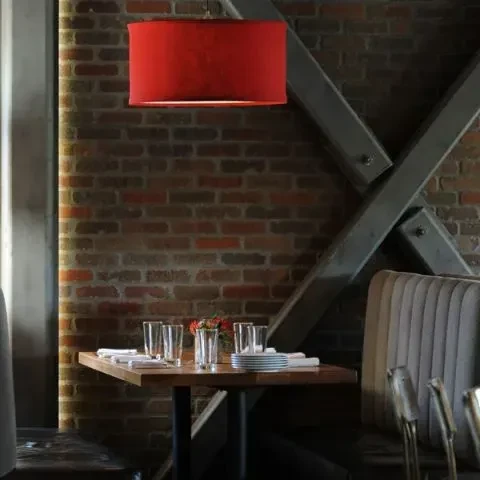 Set wooden restaurant table, red lamp, exposed brick wall, booth.