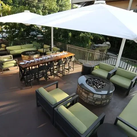 Outdoor restaurant patio with diverse seating, umbrellas, and two fire pits.