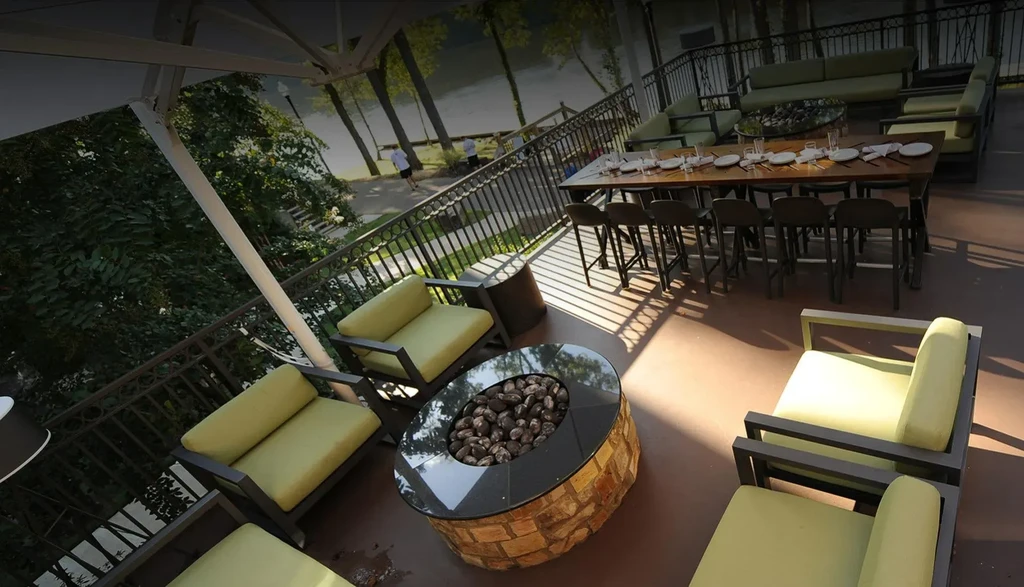 Waterside restaurant patio with lounge chairs, fire pit, and dining table.