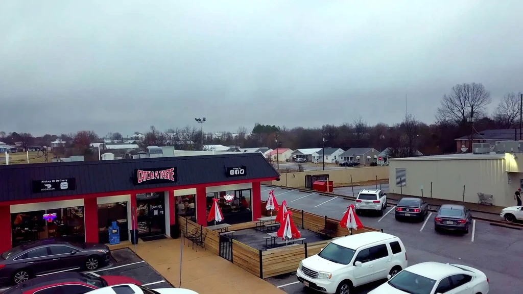 Aerial view of red 'CATCH A TASTE' restaurant with outdoor seating.