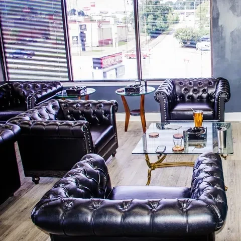 Empty lounge with dark tufted leather furniture and ashtrays.