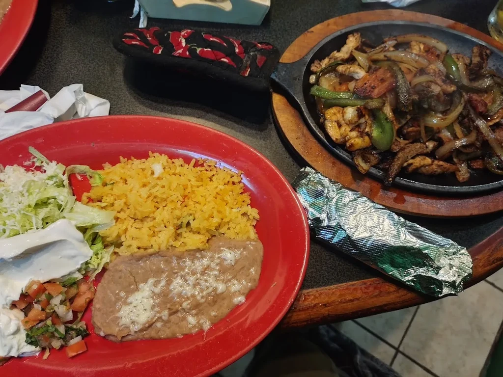 Sizzling chicken shrimp fajitas and a bean, rice, cheese plate.