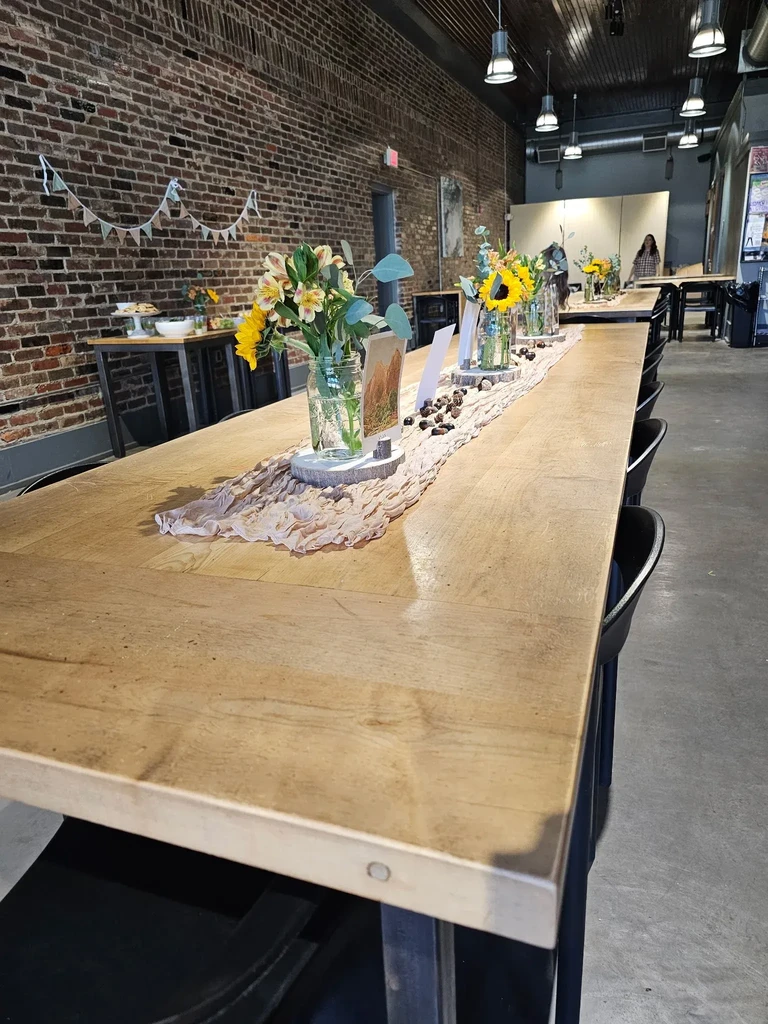 Rustic wooden table with sunflower centerpieces, nuts, and brick wall.