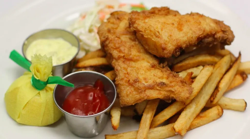Classic crispy fish and chips with fries, tartar, ketchup, and lemon.