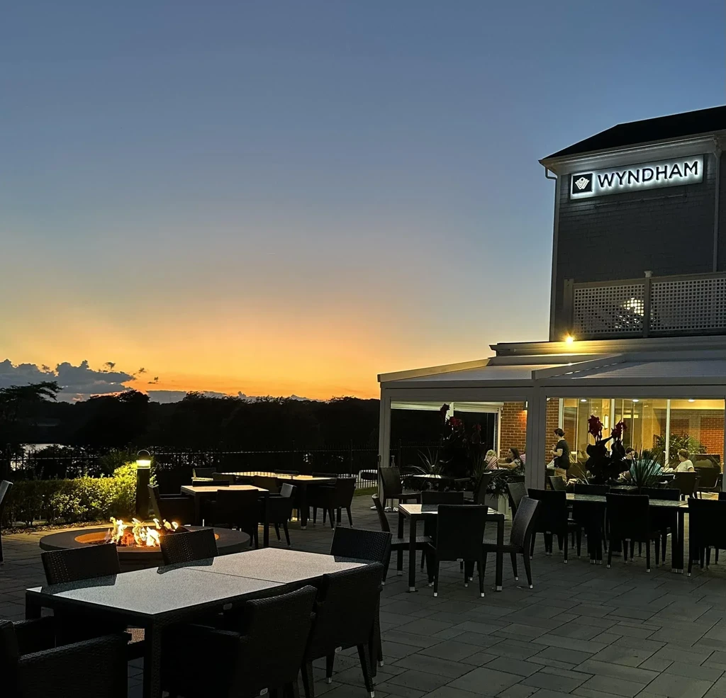 Wyndham outdoor patio at sunset with fire pit and water.