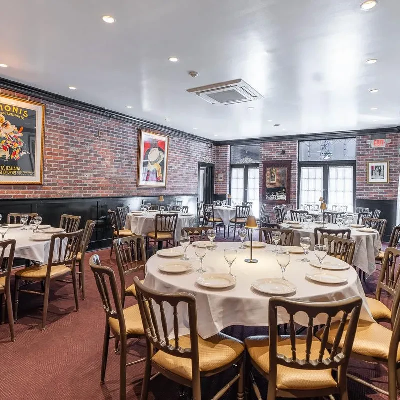 Empty fine dining room with brick walls and meticulously set tables.