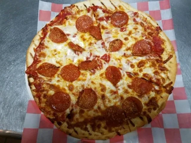 Pepperoni pizza cut into slices, with melted cheese and curled pepperoni.